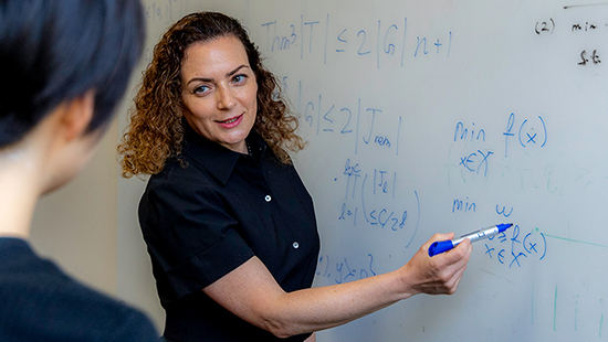 student working on formula on a white board